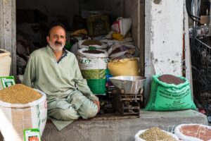 Man sitting surrounded by bags of grain, Srinagar Nowhatta, Jammu and Kashmir, India.