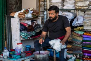 A man with fabric in a pot of dye, Jamia Market, Srinagar Nowhatta, Jammu and Kashmir, India.