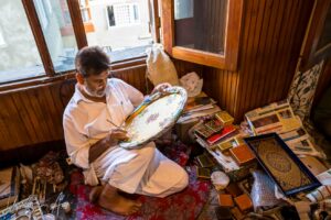 Craftsman painting a paper mache platter, Kawoosa Arts and Crafts, Srinagar, Jammu and Kashmir, India.