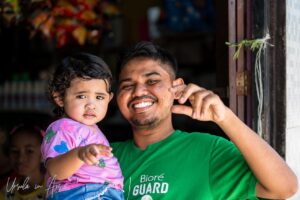 Environmental portrait: smiling man with an infant girl, Doom, Southwest Papua, Indonesia.