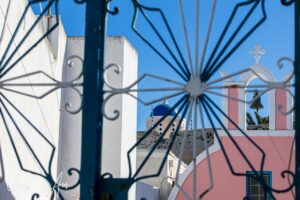 View of an Orthodox church through a wrought iron gate, Oia, Santorini Greece.