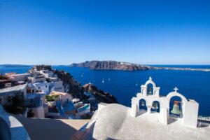 Four bells and the Castle of Oia against the caldera, Santorini, Greece.