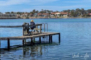 Seated fisherman on a pier, Merimbula Boardwalk, NSW Australia