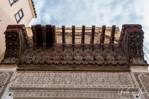 Ornamental wooden facade overhead on a tall building Meknes medina, Morocco.