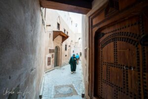 Woman in black robes in a winding corridor, Meknes medina, Morocco.