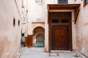 Carved wooden door and ornately tiled fountain, Meknes medina, Morocco.