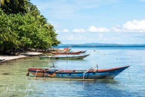 Outrigger canoes on still blue waters, Coral Triangle, Pulau Soop Indonesia