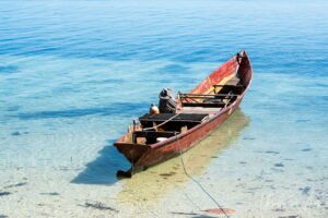 Wooden rowboat on still blue waters, Coral Triangle, Pulau Soop Indonesia
