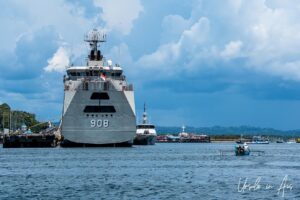 A large naval ship and a small outrigger canoe in sorong Harbour, Indonesia