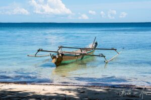 Outrigger canoe on still blue waters, Coral Triangle, Pulau Soop Indonesia