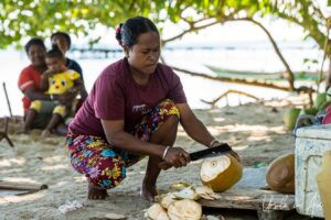 A woman cutting a fresh coconut, Pulau Soop Indonesia