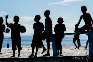 Young boys silhouetted against a blue sky, Pulau Soop Indonesia
