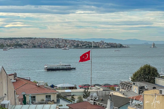 View towards Asia across the Bosphorus with a Turkish flag flying over the rooftops, Istanbul.