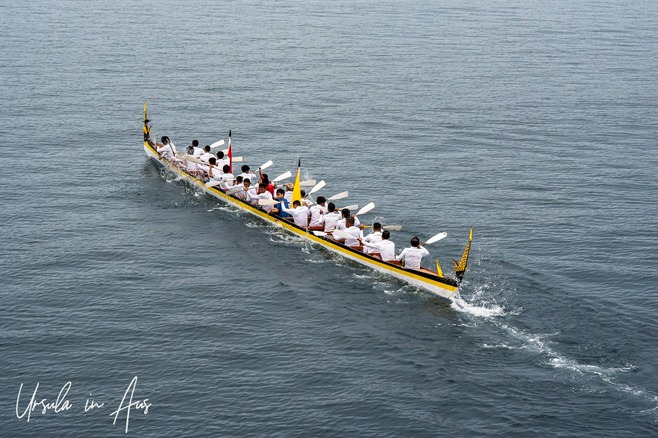 Men in white paddling a kora kora, Banda Caldera, Indonesia