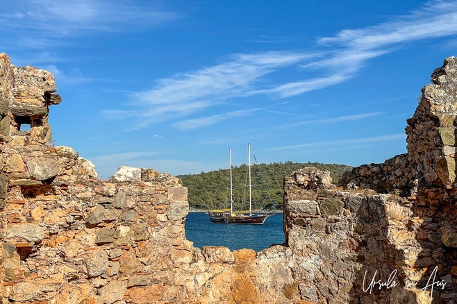 A gulet framed by the window of Kitsak Church, Cedar Island, Gulf of Gökova, Türkiye.