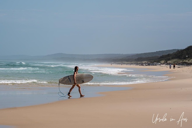 A surfer walks away from the waters at Main Beach, Stradbroke Island, Australia.
