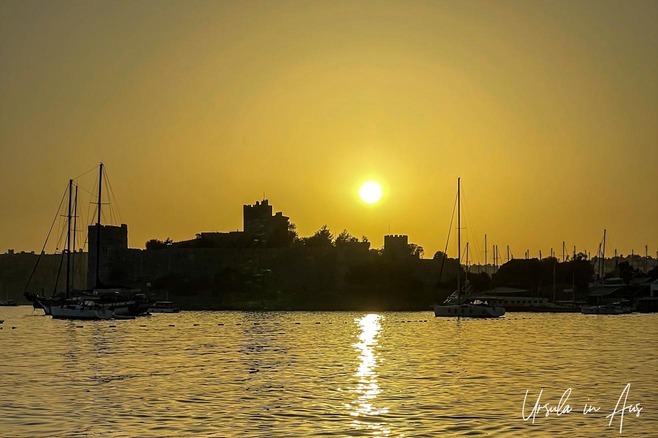 A yellow sunset over Bodrum harbour and castle, Türkiye.