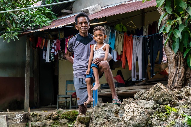 Environmental portrait: older man with a pre-schooler on his knee, DesaTumbur, Yamdena, Indonesia.