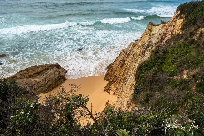 Red-brown cliff face, golden sand and turquoise waters, Mimosa Rocks National Park, NSW Australia